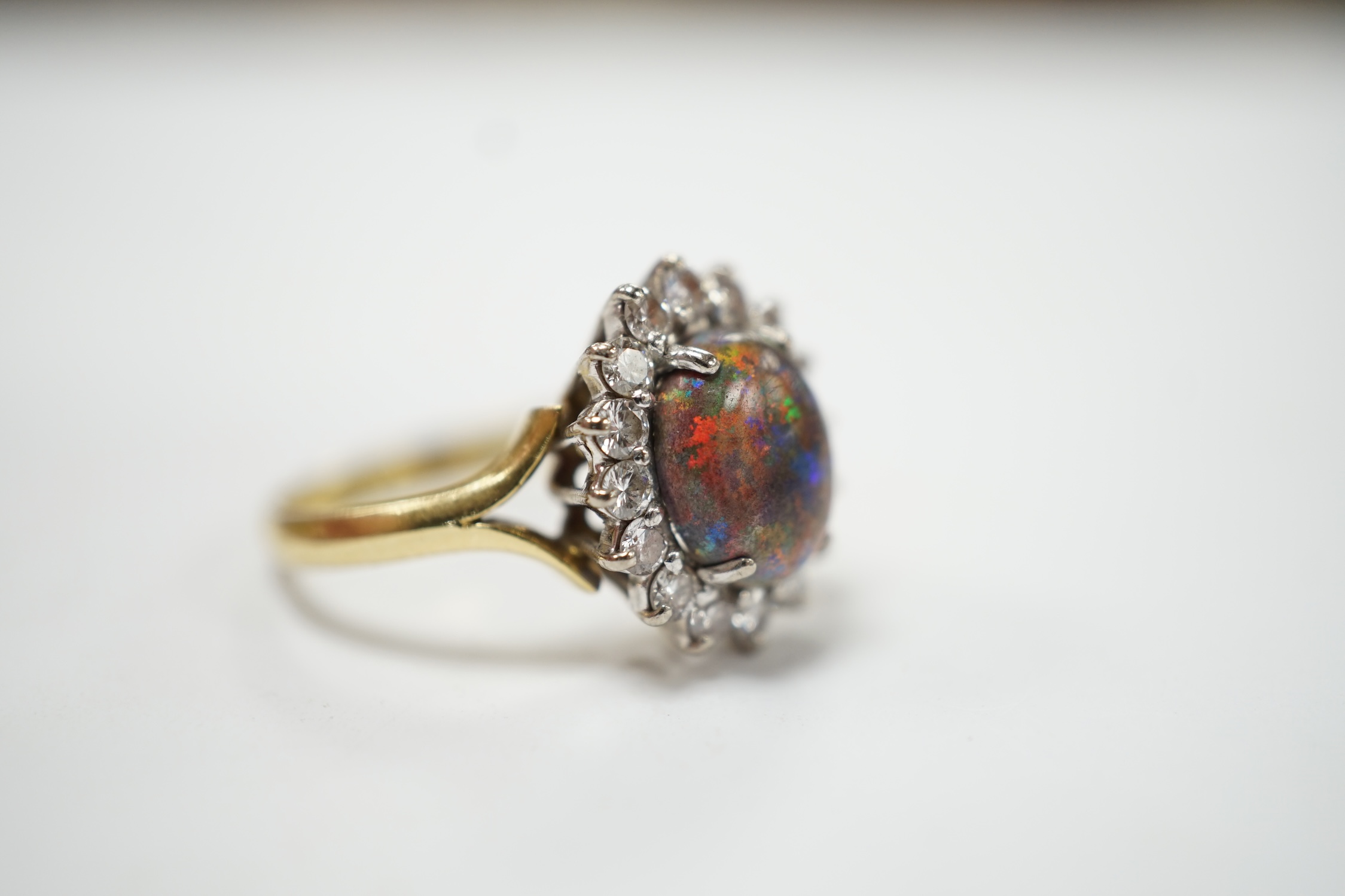 An 18ct, black opal and diamond set oval cluster ring, size P/Q, gross weight 5.4 grams. Fair condition.